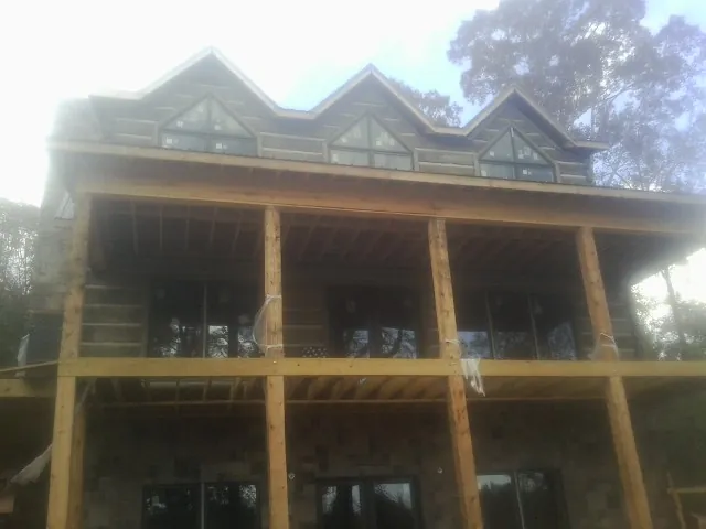 Dormers and porch framing on a large log home under construction — Roof Coating work by our crew in Walkerton