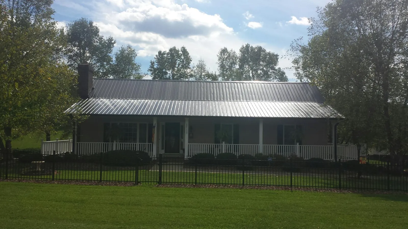 Gray metal roof on a brick ranch with a full width front porch — Gutter Guard Installation work by our crew in Walkerton