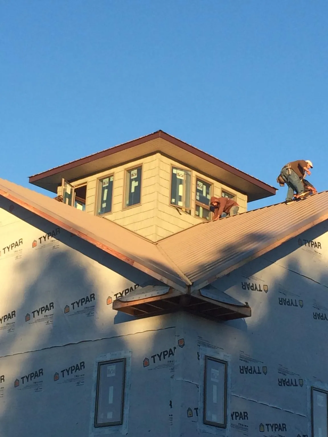 Roofers working around a rooftop cupola on a new metal roof at sunset — Roof Waterproofing in Walkerton by Roofing Brothers